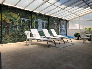 a group of white chairs in a room with a mural at Nobile Hotel Solar del Acuario in Salto