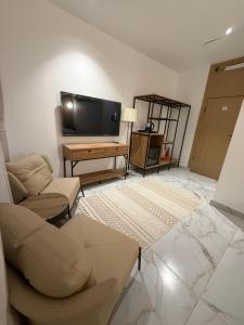 a living room with a couch and a flat screen tv at نزل عطيف - وصول ذاتي in Al Kharābah