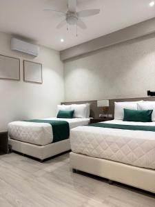 two beds in a bedroom with a ceiling at Posada Itza Peten in Santa Elena