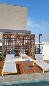 a rooftop deck with two beds and a pool at Apto Stúdio Liberdade novíssimo in São Paulo