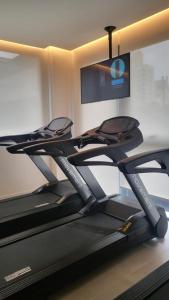 a gym with two treadmills and a flat screen tv at Apto Stúdio Liberdade novíssimo in São Paulo