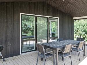 a wooden table and chairs on a deck at 8 person holiday home in Melby in Melby