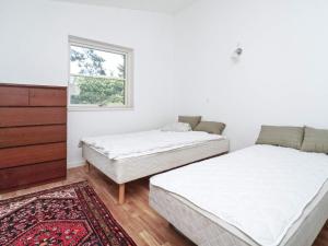 two beds in a white room with a window at 8 person holiday home in Melby in Melby