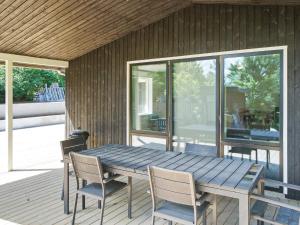 a wooden table and chairs on a deck with a house at 8 person holiday home in Melby in Melby