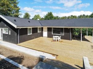 a large wooden deck in front of a house at 8 person holiday home in Melby in Melby +34 photos