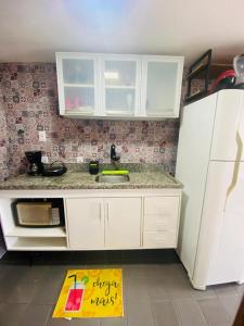 a kitchen with white cabinets and a yellow sign on the floor at Vitória Marina Flats in Salvador