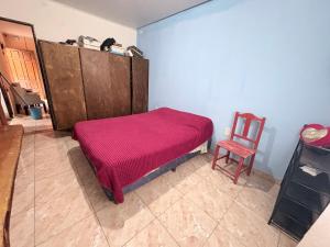 a bedroom with a pink bed and a chair at Casa saavedra in Estación Ramallo