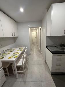 a kitchen with white cabinets and a table with chairs at Rooms Moscavide quartos in Lisbon