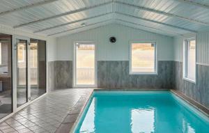 an empty swimming pool in a house with windows at Awesome Home In Hvide Sande With Sauna in Hvide Sande +27 photos