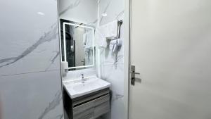 a white bathroom with a sink and a mirror at Ammania Hotel in Amman