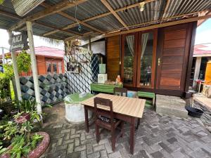 an outdoor patio with a wooden table and chairs at Naca Homestay in Manado