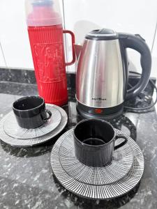 a counter with two cups and a tea pot and a coffee at Quarto com area de descanso in Foz do Iguaçu