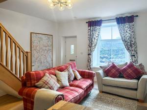 a living room with a red couch and a chair at Croft House Cottage in Hebden