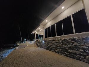 a building with a stone wall at night at Costa Moriah Manticao PH in Manticao