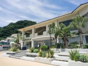 a building with palm trees in front of it at Good Fellows Resort in Kagoshima