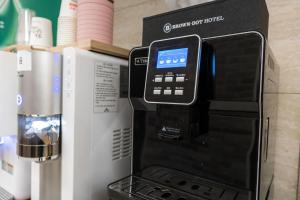 a coffee machine with a cell phone on top of it at Browndot Hotel Godeok newtown in Pyeongtaek