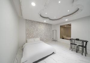 a white bedroom with a bed and a table at Gunsan Hasen Hotel in Gunsan-si +12 photos