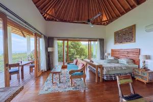 a bedroom with a bed and a table and chairs at LiRi Villa - Ocean, hills, valley view in Lovina