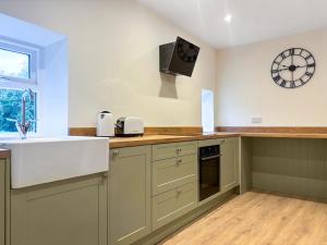 a kitchen with a sink and a clock on the wall at Croft House Cottage in Hebden