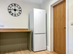 a white refrigerator in a kitchen with a clock on the wall at Croft House Cottage in Hebden