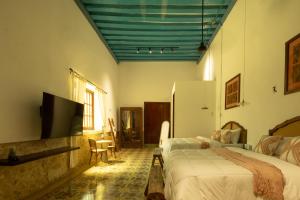 a bedroom with two beds and a flat screen tv at Dos Almas Casa Boutique in Campeche