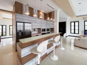 a kitchen with a bar with white stools in it at The Lavana Dzawani Villa Berawa Kuta Bali 3 Bedroom Villa in Canggu