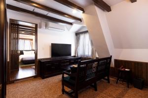 a living room with a television and a bedroom at Matsumoto Hotel Kagetsu in Matsumoto