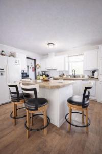 a kitchen with white cabinets and a counter with three chairs at Family Country Retreat w Pool, Games & Fire Pit in Clewiston +60 photos