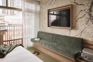 a bedroom with a green couch and a tv at The Ultimo in Sydney