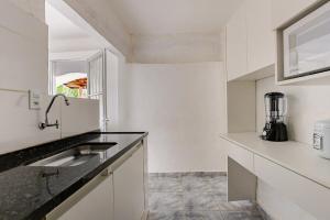 a white kitchen with a sink and a blender at Aqui, a vista é arte em Barequeçaba in São Sebastião