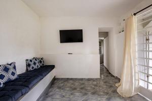 a living room with a couch and a tv on the wall at Aqui, a vista é arte em Barequeçaba in São Sebastião