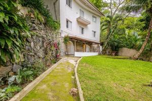 a house with a stone wall and a yard at Aqui, a vista é arte em Barequeçaba in São Sebastião