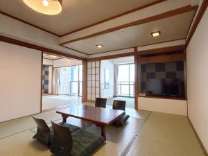 a dining room with a table and chairs and a tv at Uomisaki Hotel in Atami
