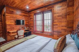a bedroom with wooden walls and a bed and a desk at Phetchalern serviced apartment in Vientiane
