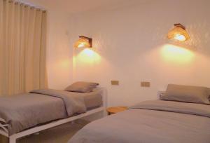 a bedroom with two beds and two lights on the wall at Tipsea Turtle Gili Trawangan in Gili Trawangan