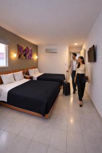 a man and woman walking through a hotel room with two beds at Hotel Interforum in León