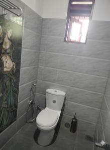 a bathroom with a toilet and a painting on the wall at DenbyD in Tennekumbura