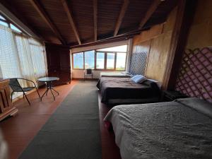 a room with two beds and a table and windows at Mansión Del Arco in San Pedro La Laguna