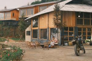 a woman sitting at a table in front of a house at Pơ Mu Mống Vàng in Bắc Yên
