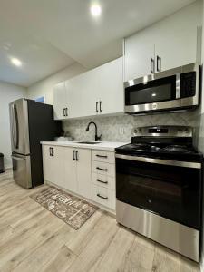 a kitchen with white cabinets and a black stove top oven at Spacious High Ceiling Lower Level Suite-New & Cozy in Vaughan