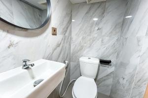 a bathroom with a toilet and a sink and a mirror at Laurel Inn Menteng in Jakarta