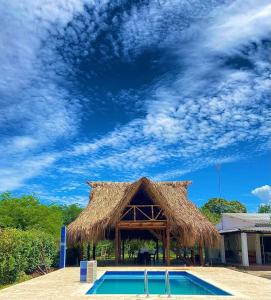 a straw hut with a swimming pool and a blue sky at Finca # 20 - Arjona in Turbaco