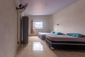 two beds in a room with a window at Apartamento para 6 com Vaga e Churrasqueira in Pará de Minas