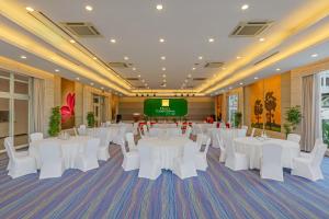 a banquet hall with white tables and chairs and a screen at Hotel Cambodiana in Phnom Penh
