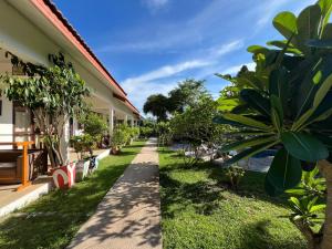 a walkway next to a building with grass and trees at Tree Roots Retreat in Rayong