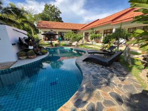 a swimming pool in front of a house at Tree Roots Retreat in Rayong +15 photos