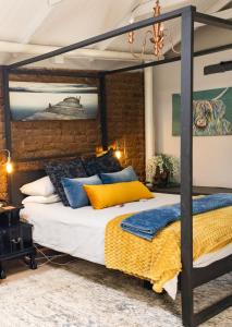 a bedroom with a canopy bed with yellow and blue pillows at 1 Queen Vic in Darling