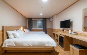 a bedroom with a large bed and a television at New Jeju Hotel in Jeju