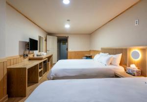 a hotel room with two beds and a television at New Jeju Hotel in Jeju +44 photos
