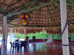 a dining room with a table and chairs under a thatched roof at Finca # 20 - Arjona in Turbaco